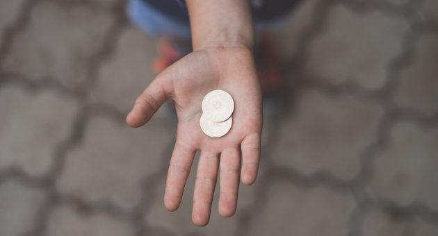 person holding two coins gifting money to a friend