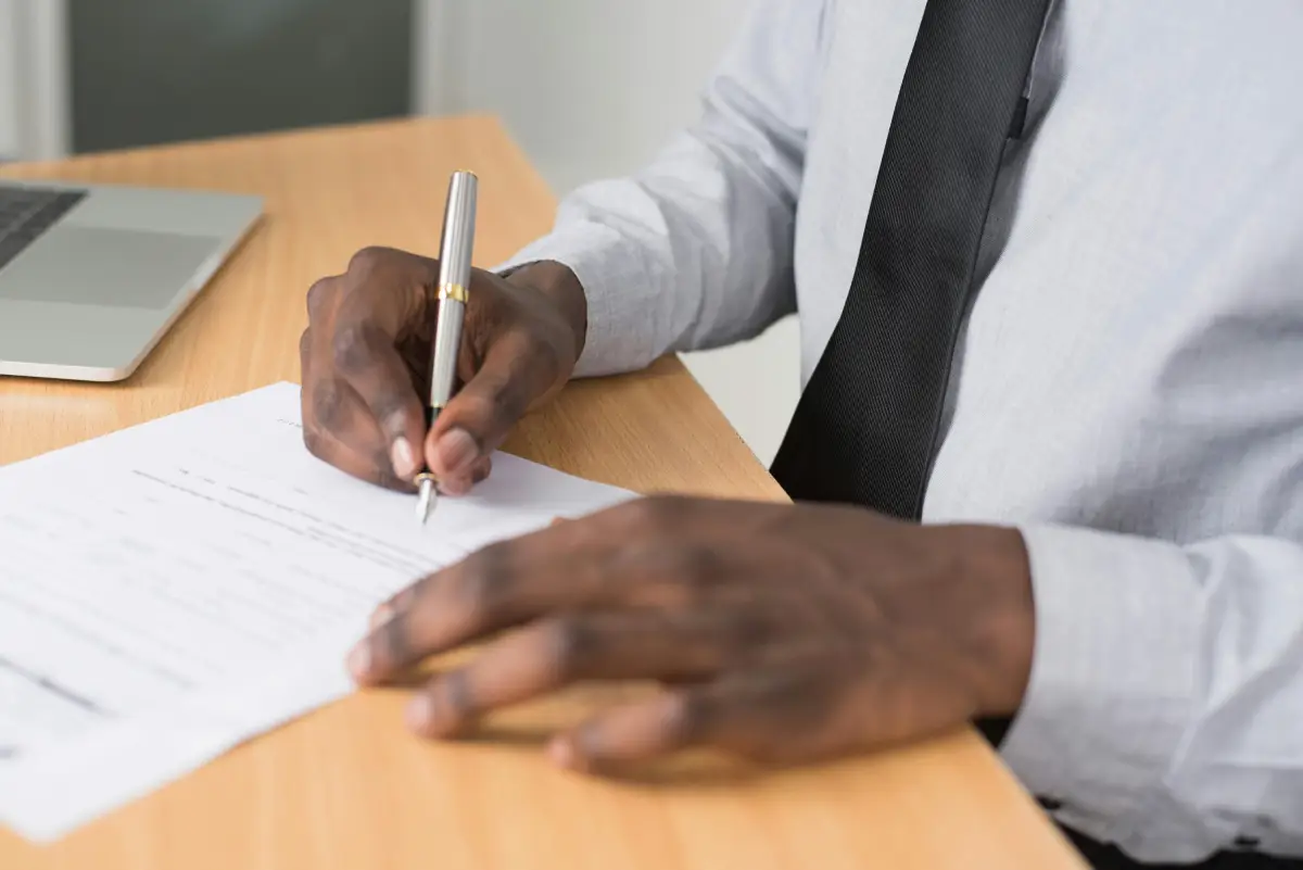 person signing paperwork after choosing life assurance vs life insurance